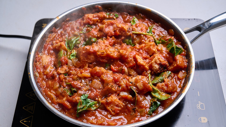 wilting spinach into tomato sauce in skillet
