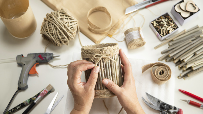 Overhead view of person decorating a DIY basket with tools and materials on a table.