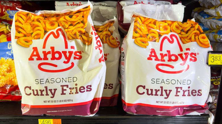 two packages of frozen Arby's Seasoned Curly Fries in a grocery store freezer
