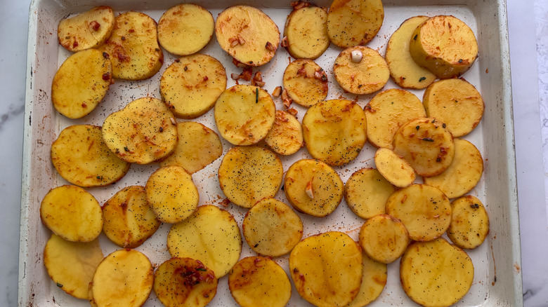 Sliced potatoes spread out on sheet pan