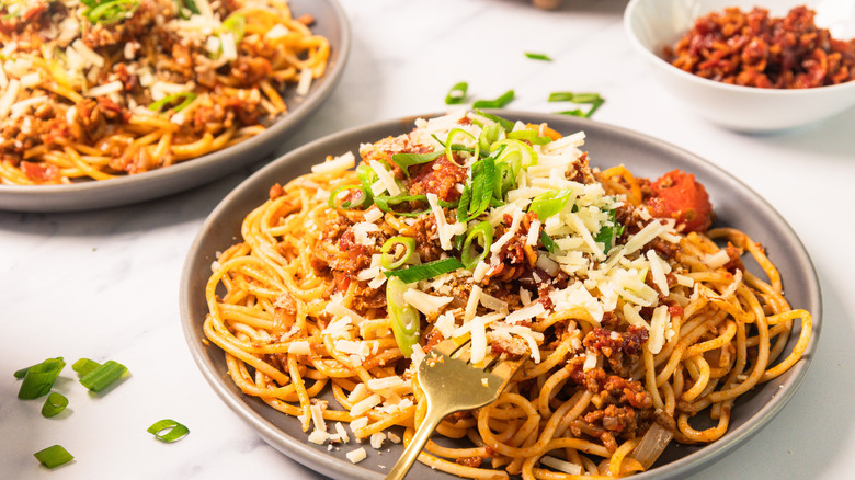 A plate of bourbon-infused cowboy spaghetti with fork in it, and another plate in background