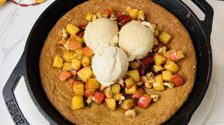 Apple blondie skillet topped with spiced apples and vanilla ice cream scoops