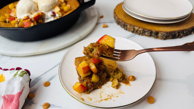 Serving of apple blondie on plate with fork holding bite in front