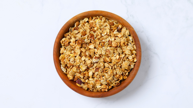 Granola in wooden bowl on white surface