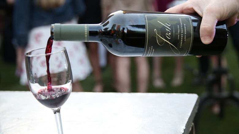 Someone pours a bottle of a Josh Cellars cabernet sauvignon Lodi Reserve into glass