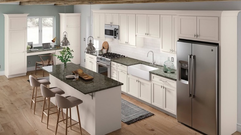 A kitchen with granite counters and white cabinetry