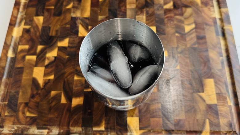 Dark liquid and ice in cocktail shaker