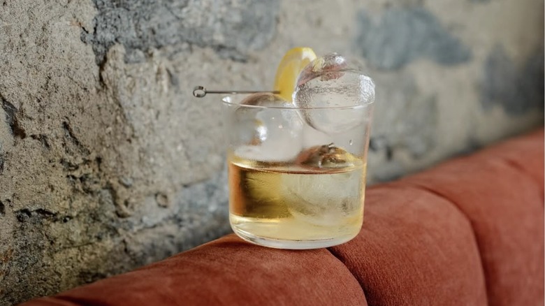 cocktail on the back of a orange sofa next to stone wall at Bar Bisou Bisou in Old Montreal