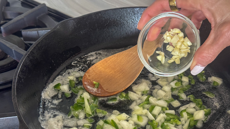hand adding garlic to skillet