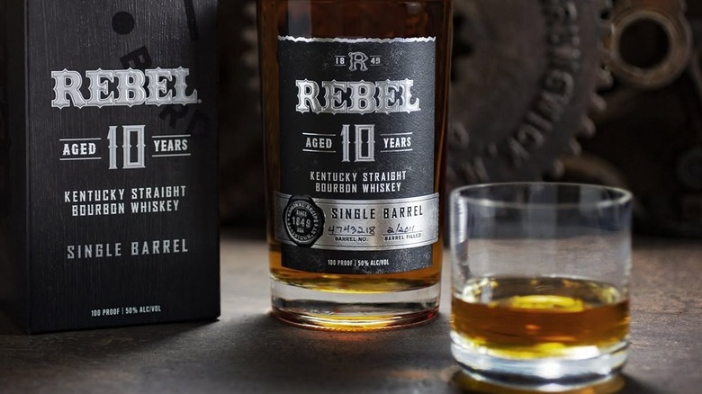 A close shot of a bottle of Rebel 10-year Single Barrel with its packaging and a filled glass either side