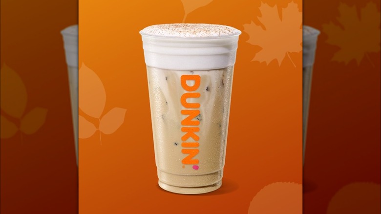 Dunkin' Pumpkin Patch Cloud Latte in plastic cup against orange background