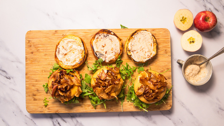 Caramelized apple burgers on a cutting board being assembled