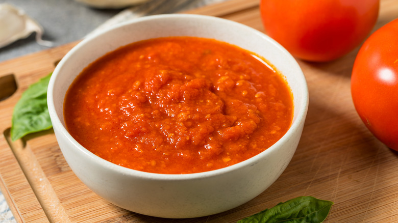 Close-up of a small white bowl of pizza sauce.