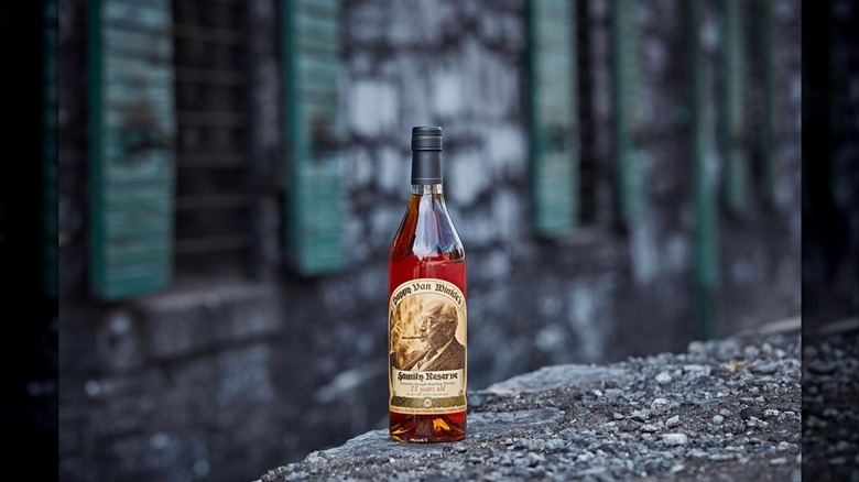 A bottle of Pappy Van Winkle 15-year placed on a stone wall with a blurred building in the background
