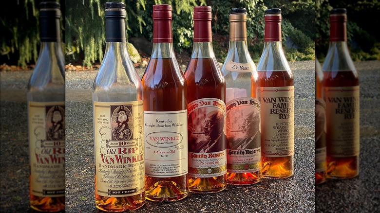 A line-up of five Pappy Van Winkle bottles placed on the ground with two almost empty
