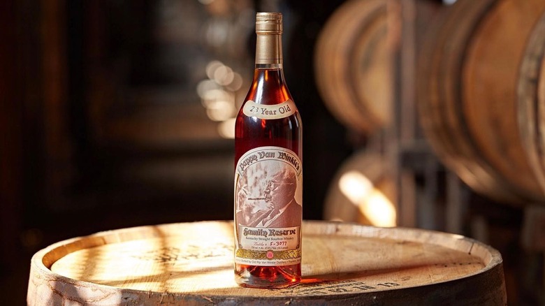 A Pappy Van Winkle 23-year bottle posed on the top of a barrel in the middle of a warehouse