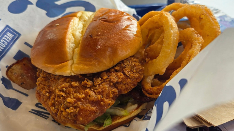 A chicken sandwich and onion rings from Culver's atop branded wrapper paper