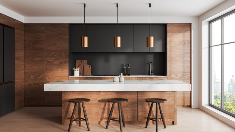 Dark wood kitchen with marble countertops and black upper cabinets.