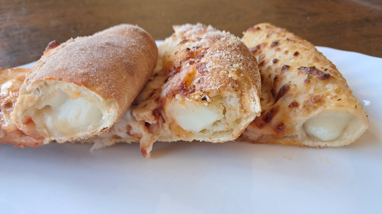 Side view of three slices of stuffed crust pizza with cheese oozing out