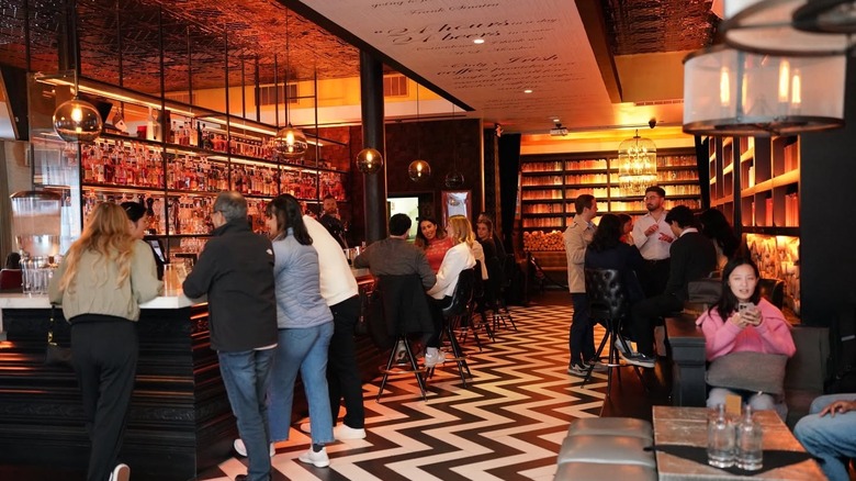 Customers enjoying drinks at bar with poetry inscribed on ceiling