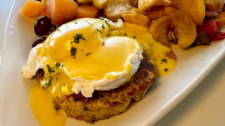 Crab cake with poached egg on plate with potatoes