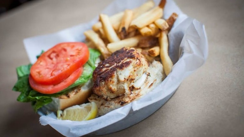 Crab cake in basket with fries, lettuce, tomato, and lemons