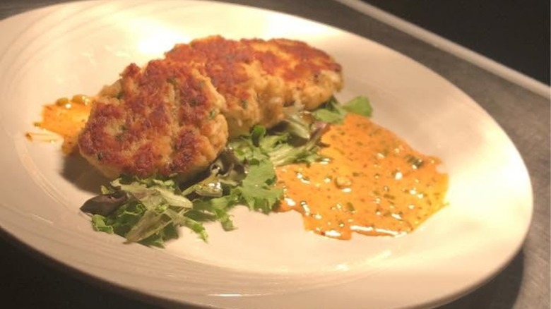 Two crab cakes with greens and sauce