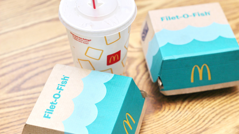 Filet-O-Fish boxes beside McDonald's soft drink on table