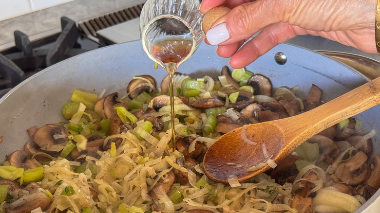 hand adding vinegar to pan