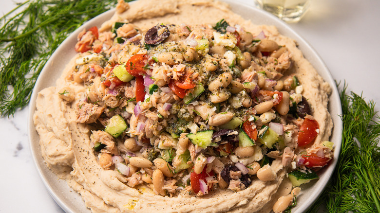 White bean and tuna salad with dill around beside a glass of wine