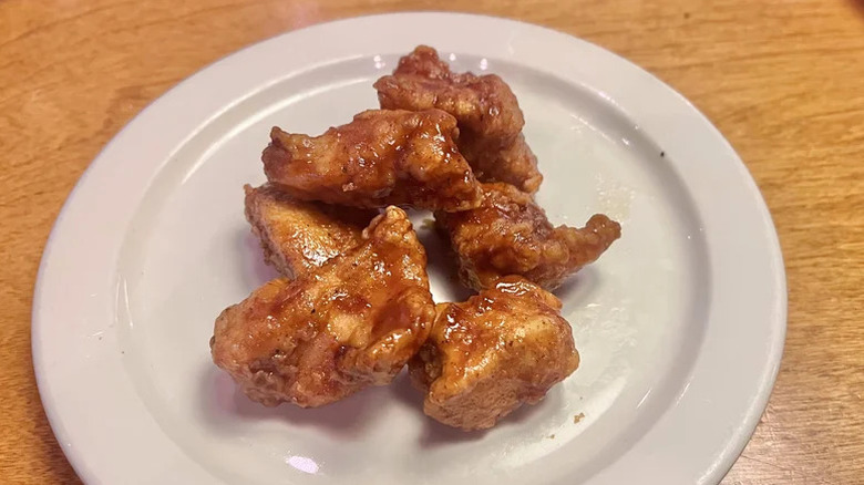 Several boneless chicken wings glistening with a brown sauce sitting on a white plate