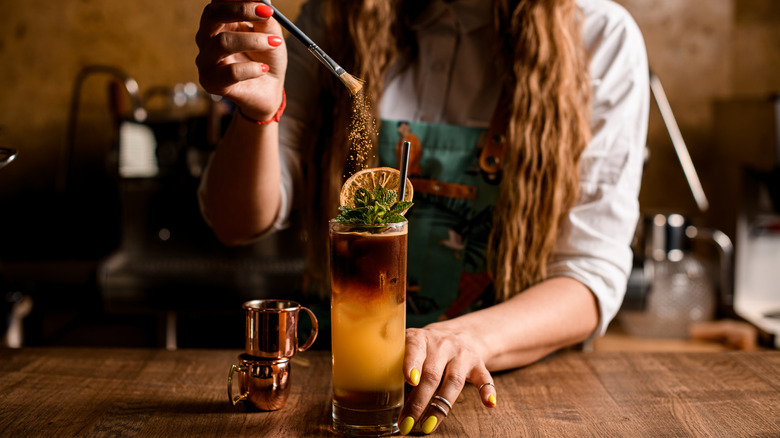 A bartender dusting a cocktail with spices