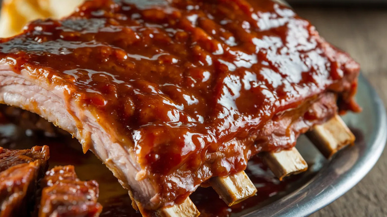 A plate of glazed shiny ribs covered in barbecue sauce.
