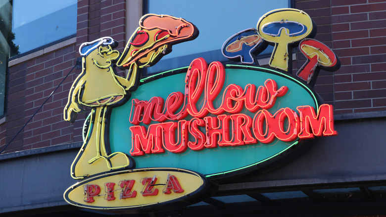 Neon sign for Mellow Mushroom featuring its Mel O. Mushroom mascot holding a pizza slice