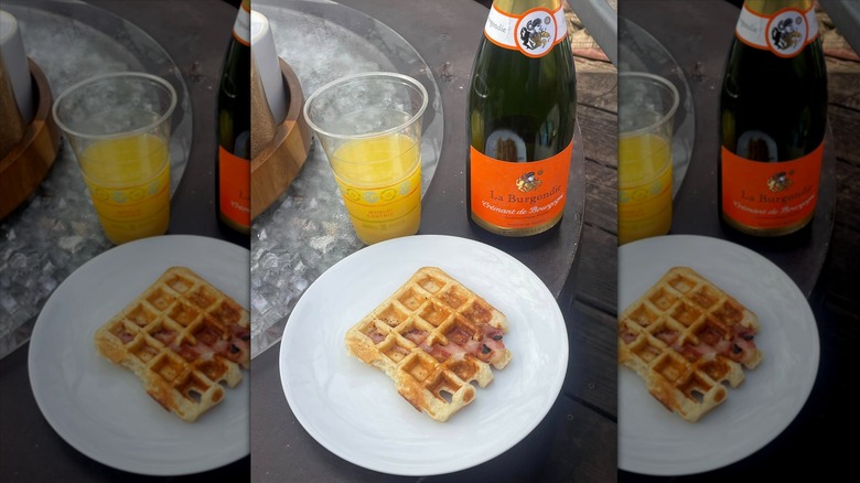 Bottle of La Burgondie Crémant de Bourgogne next to glass of orange juice and waffle