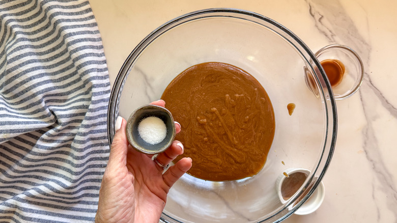 hand adding salt to bowl